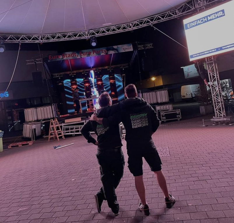 Zwei Mitarbeiter vor einer LED Wand